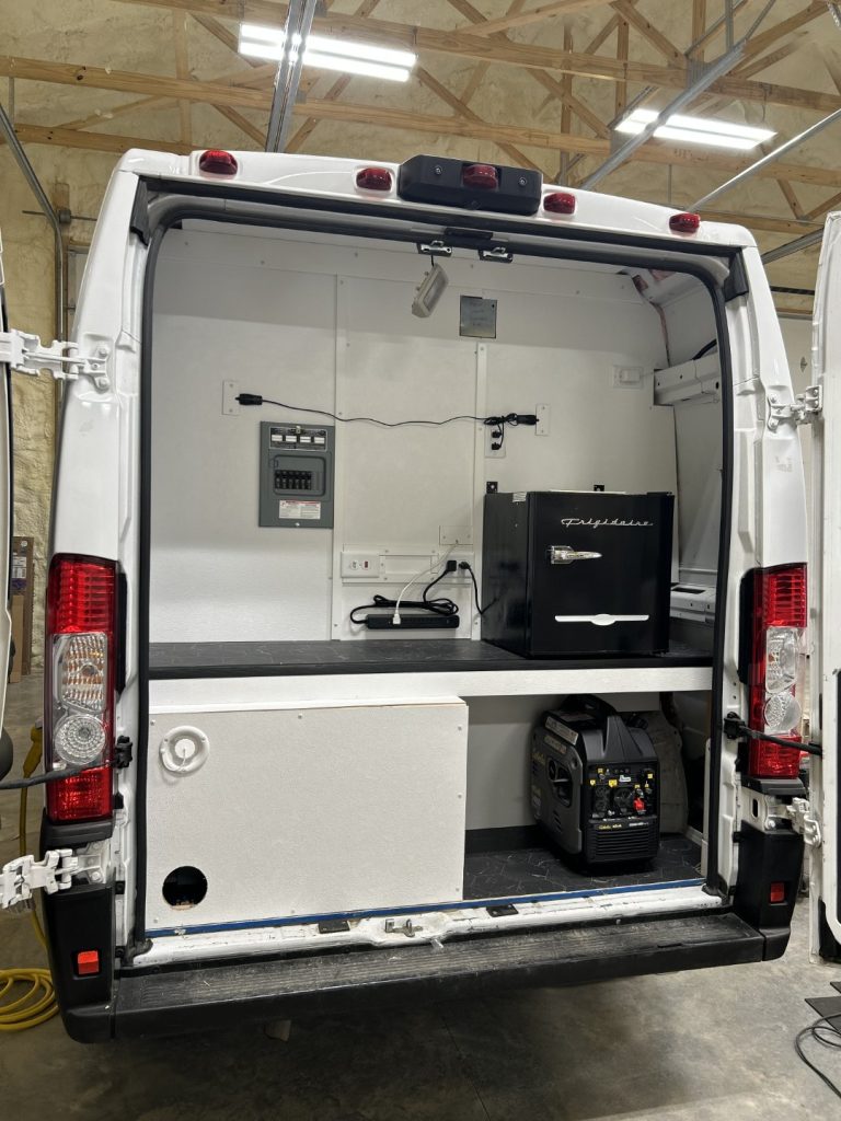 Barber Mobile shampoo bowl station with black cabinetry, backlit mirror, barber pole, and overhead Barber Mobile ceiling sign built by Alexander's RV