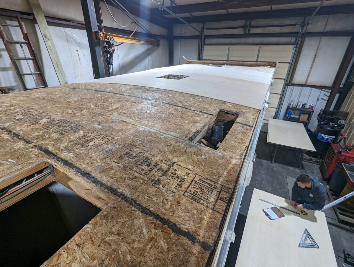 High-angle view of a partially replaced RV roof in a workshop.